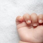 Newborn baby hand in white bed