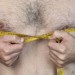 man with chest hair measuring it with tape measure