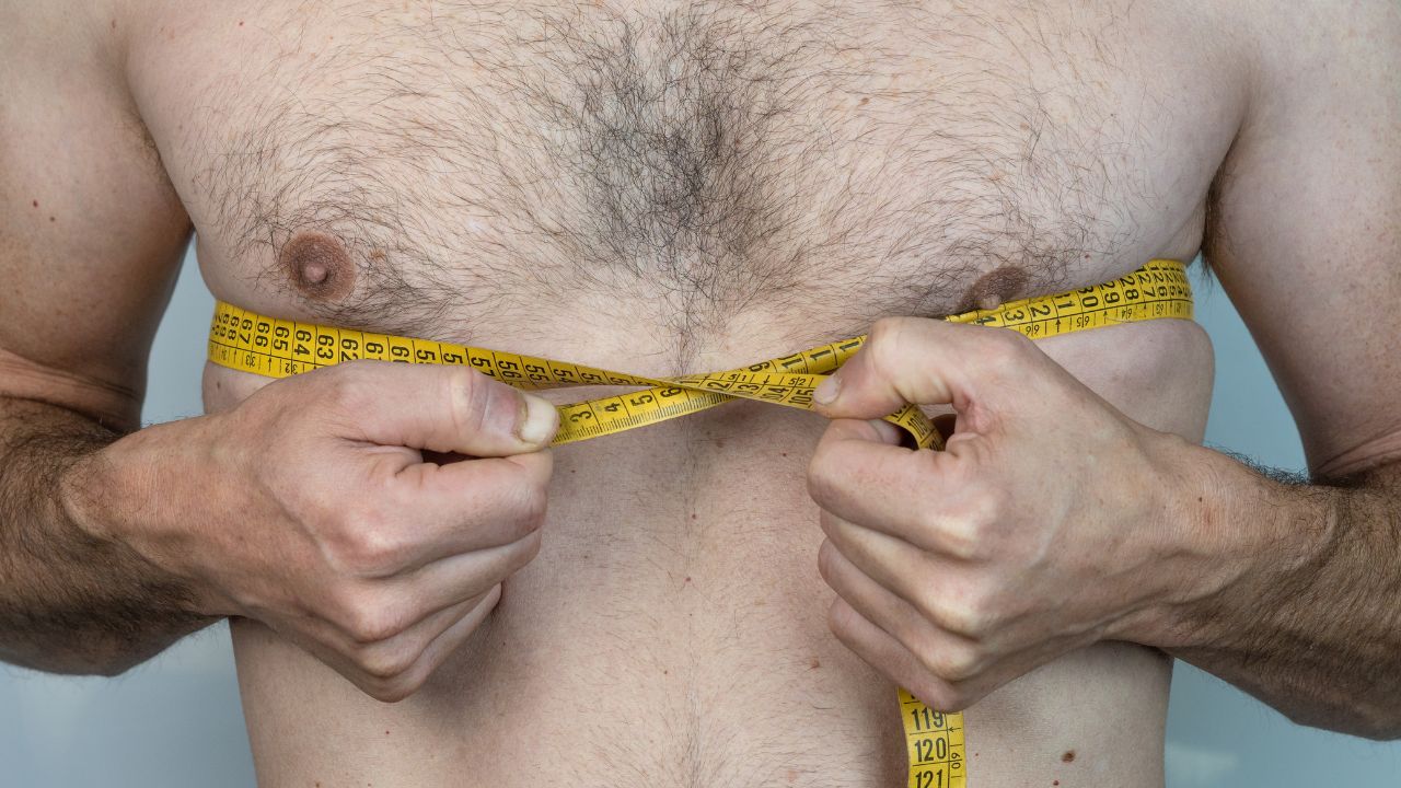 man with chest hair measuring it with tape measure